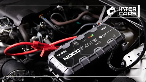 Prijenosni punjač Noco Boost X GBX155 sa crvenim kablovima u motoru automobila.