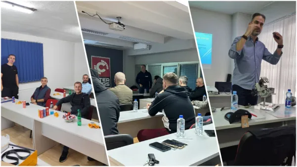 Grupa ljudi prisustvuje obuci u učionici sa projektorom i materijalima na stolovima.