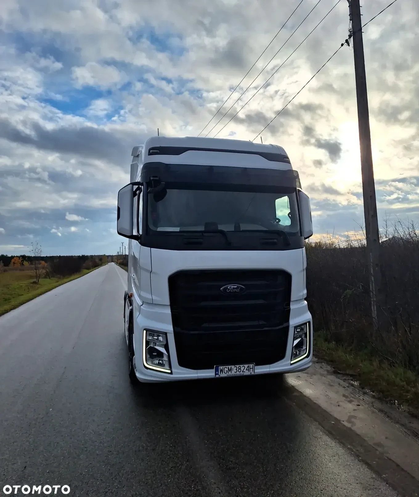 Widok na białą ciężarówkę Ford stojącą na drodze w otoczeniu chmur.