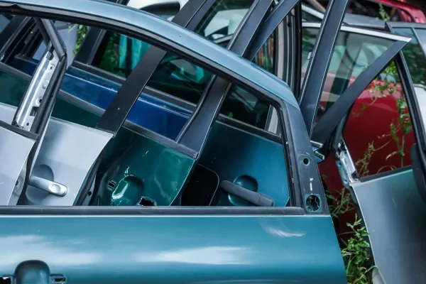Metalo laužynas su įvairių spalvų automobilių durimis.