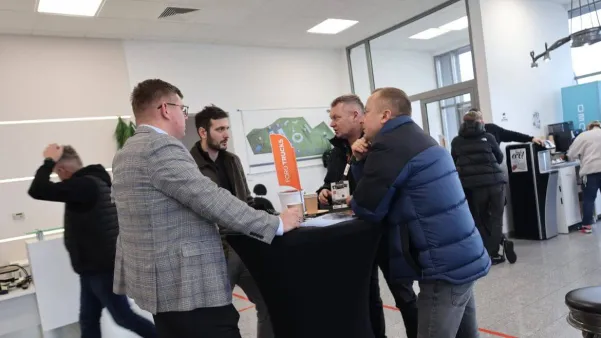 Grupa mężczyzn rozmawia przy okrągłym stole w biurze, z widocznym logo Ford Trucks.