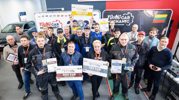 Grupė jaunųjų automobilių mechanikų su apdovanojimais ir diplomais.