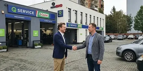 Dwóch mężczyzn uścisnęło sobie dłonie przed serwisem Q Service.