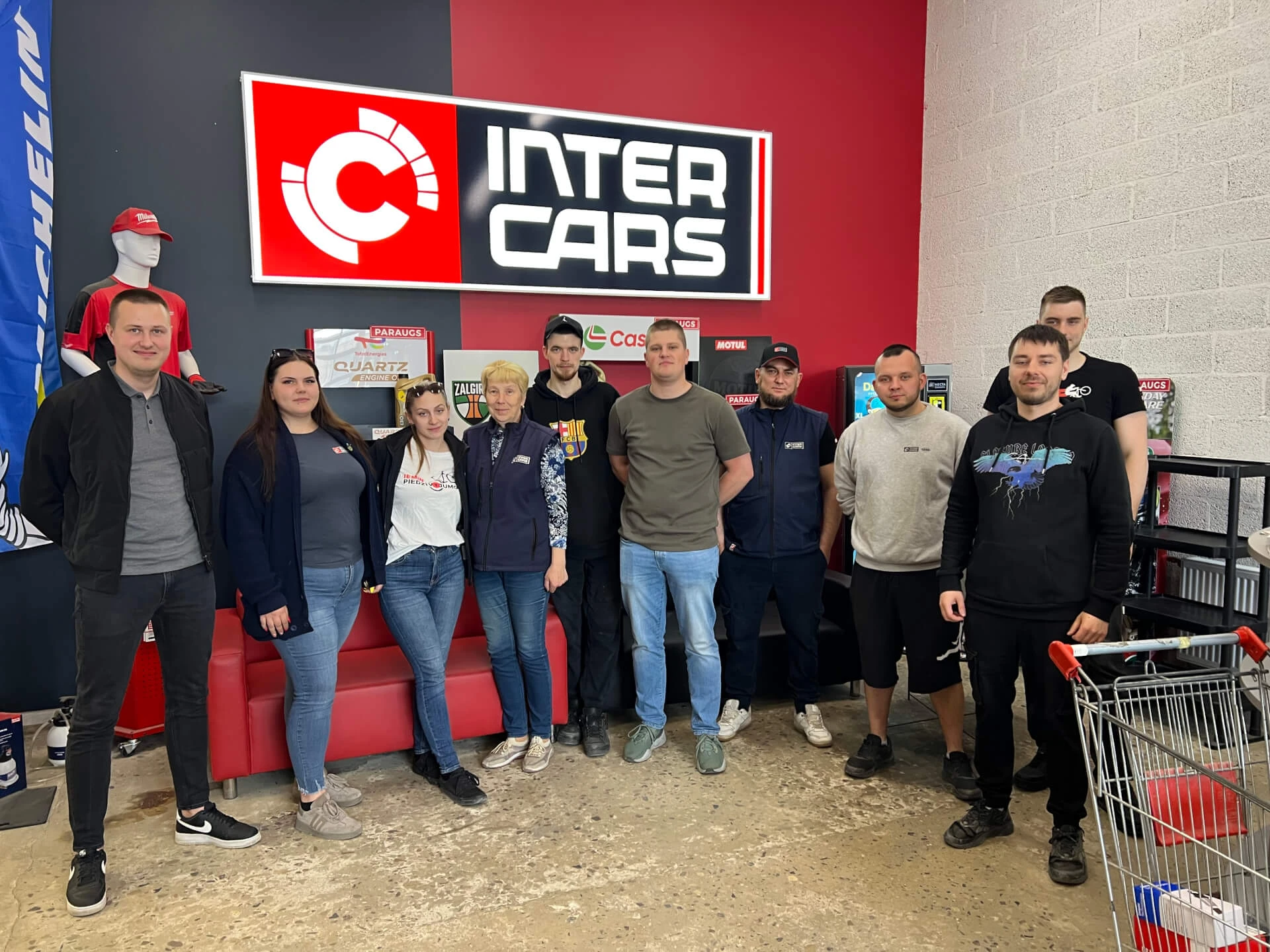 Inter Cars darbinieki pozē grupā pie uzņēmuma zīmes.