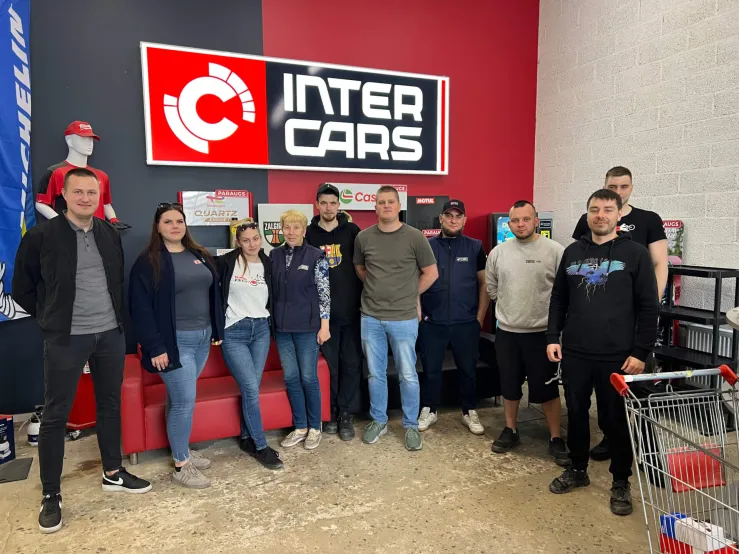 Inter Cars darbinieki pozē grupā pie uzņēmuma zīmes.