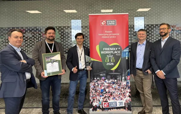 Pracownicy Inter Cars z nagrodą Friendly Workplace 2026 przy banerze firmy.