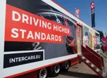 Intercars reklám a mobil bemutató járművön, 'Driving Higher Standards' felirattal.